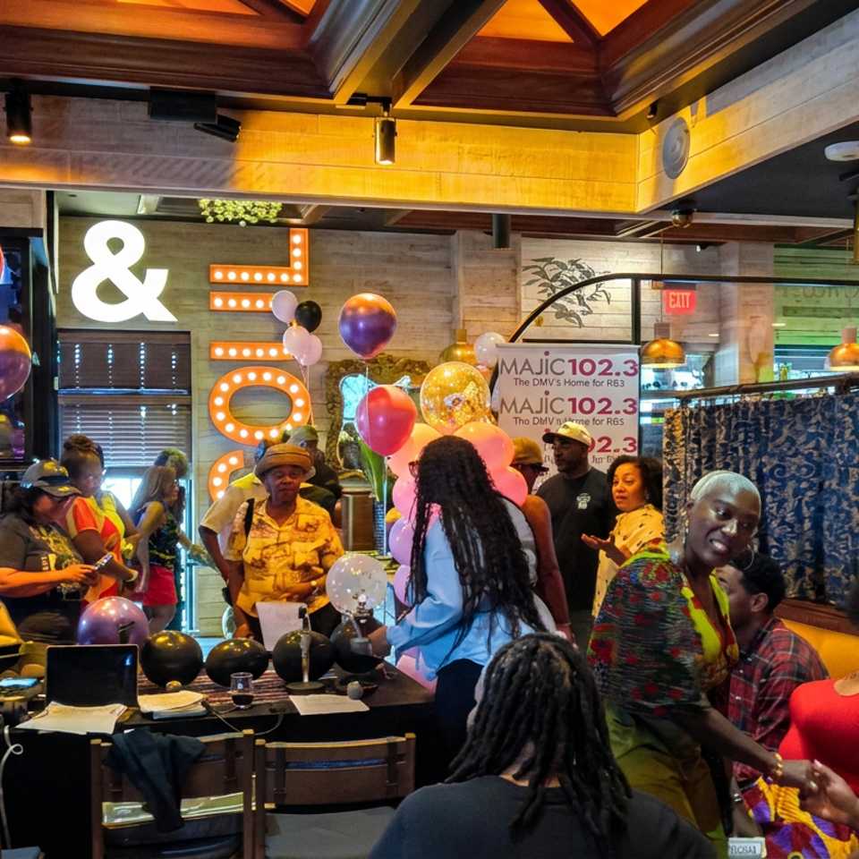 Crowded restaurant celebration with colorful balloons, guests, a DJ booth, and illuminated ampersand decorations.